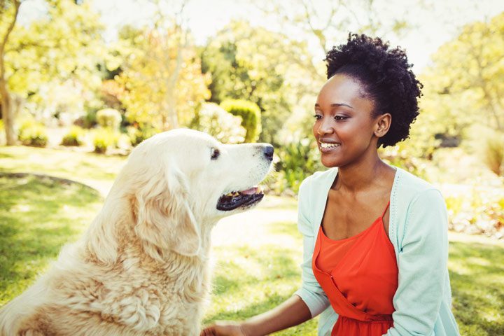 beautiful young Black woman with golden retriever outdoors - alternative therapies