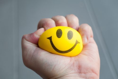 hand squeezing smiley face stress ball