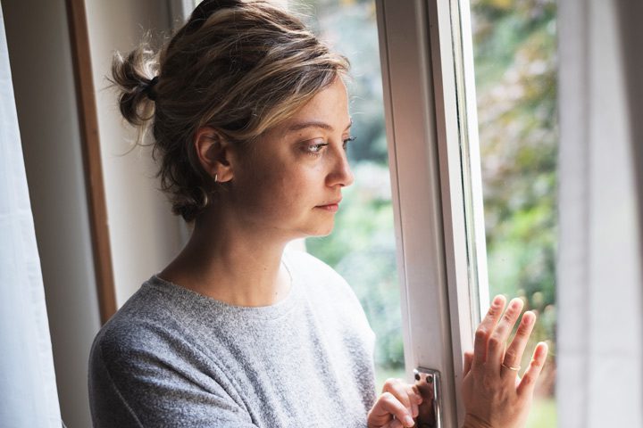 sad woman looking out window - addiction treatment