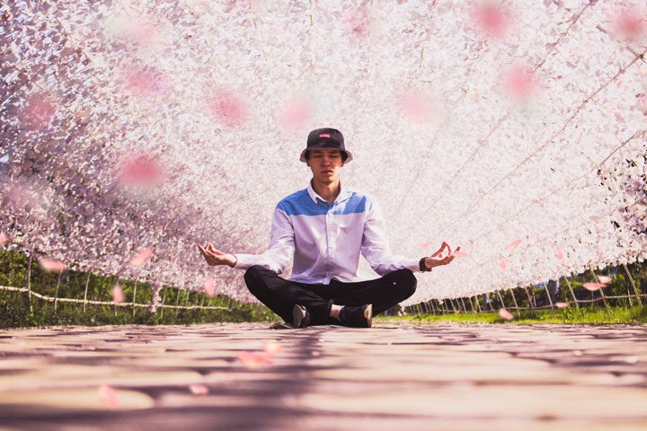 young man meditating in lotus position - meditation