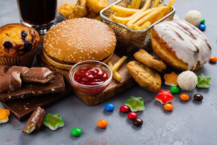 junk food on table - burger, fries, donuts, candy, etc. - food addiction