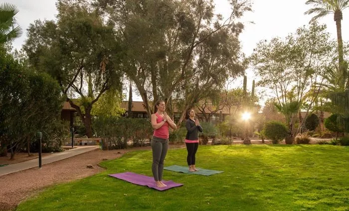 two women doing yoga in lush green courtyard - Cottonwood Tucson holistic treatment for mood disorders and addiction