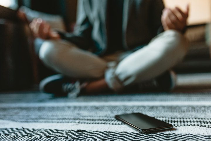 man sitting on floor with legs crossed, meditating - managing anxiety