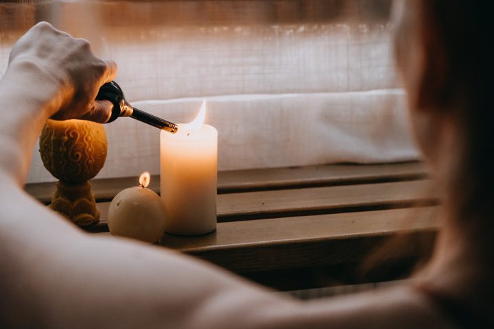 cropped shot of person lighting several candles - self-care
