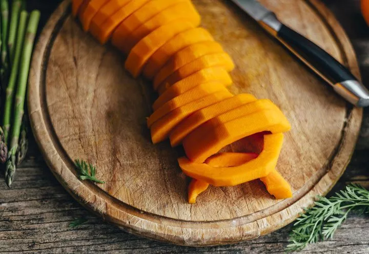 wooden cutting board with bright orange freshly cut winter squash - superfoods
